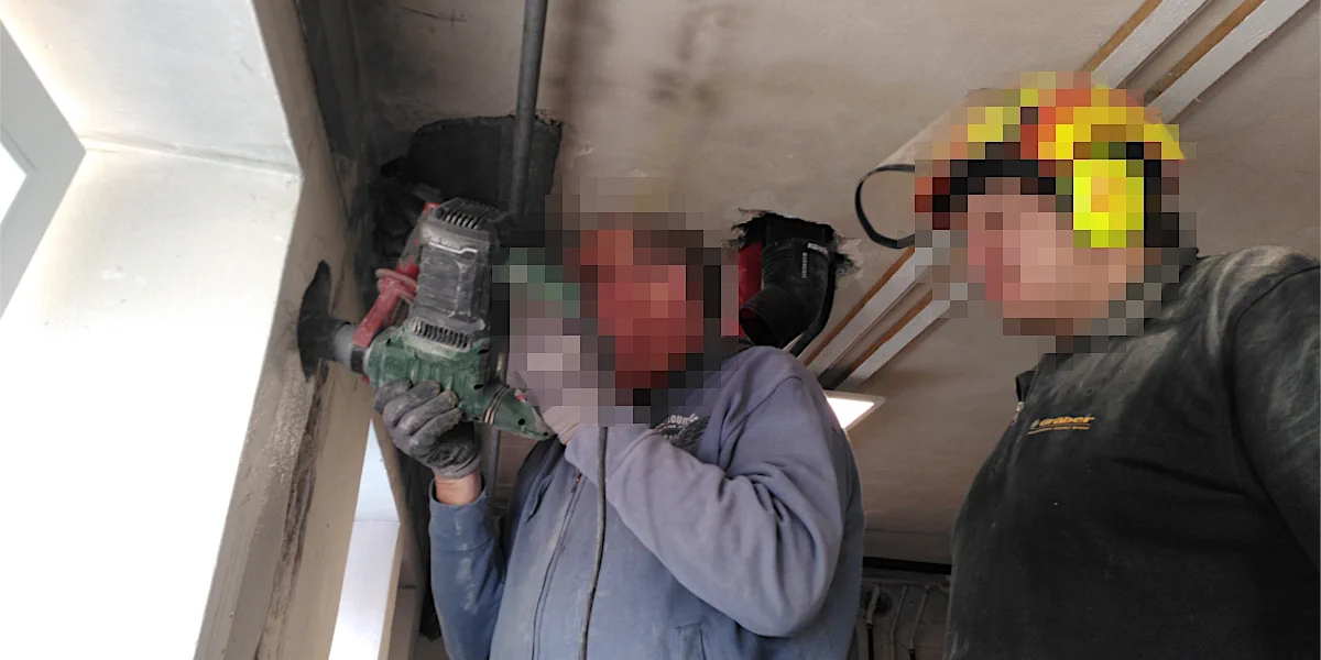 Zwei Arbeiter bohren mit einem Bohrhammer in einer Wand