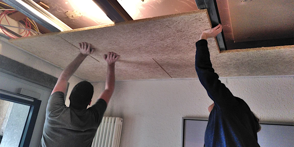 Zwei Arbeiter schrauben Akustikplatten an die Decke