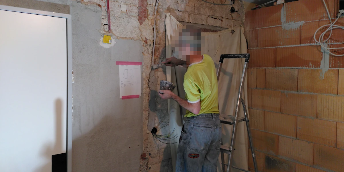 Jemand beim zuspachteln von einem Elektrokabelschlitz