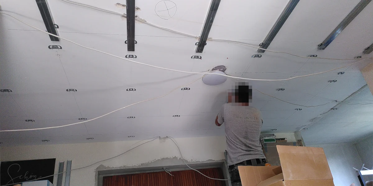 Mann der die Halter für die Deckenkonstrukion montiert