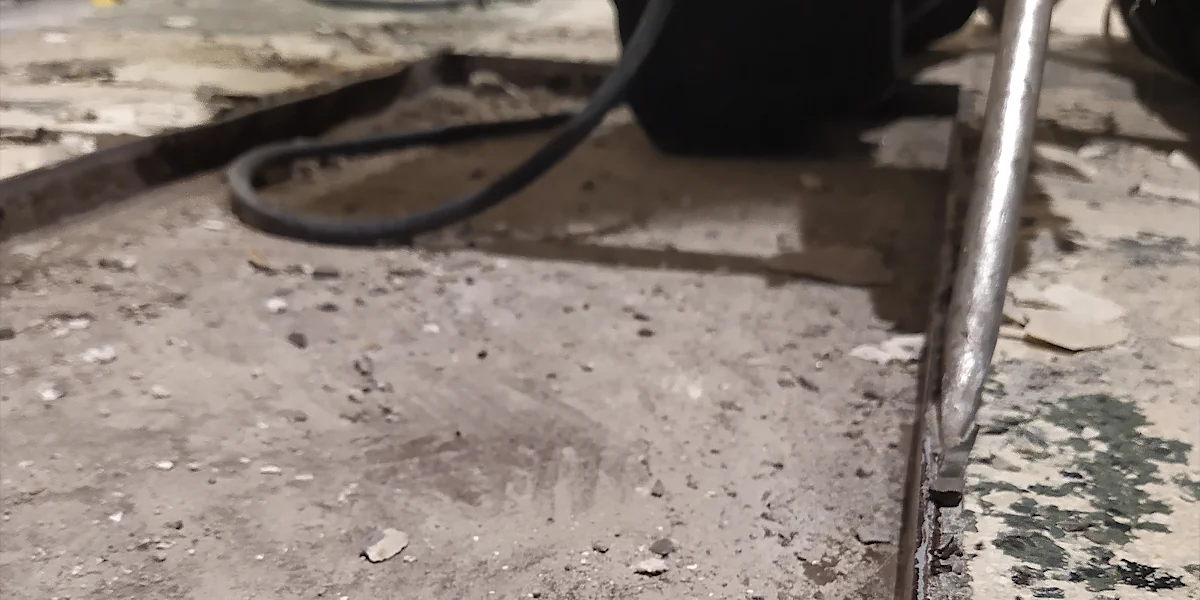 Nahaufnahme eines Bohrmeißels der einen Eisenrahme ausmeißelt