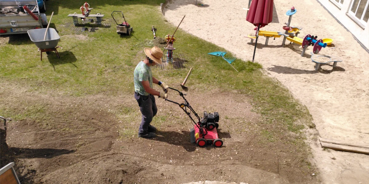 Mann mit Sonnenhut beim Vertikutieren