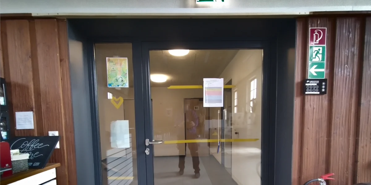 Person auf einem Gerüst verspachtelt die hohes Fenster